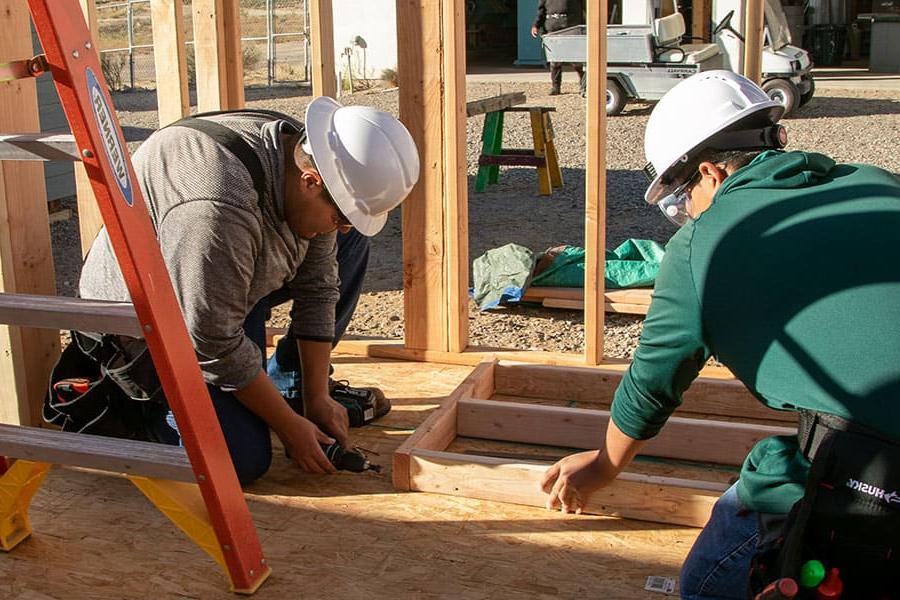 Two 火博体育 students working on framing a building