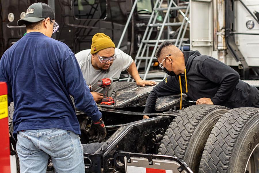 Three 火博体育 students working on a diesel engine in a truck